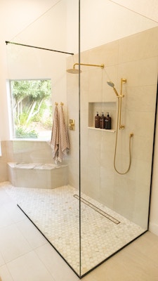 eine bodentiefe Dusche in einem modernen sandfarbenen Badzimmer